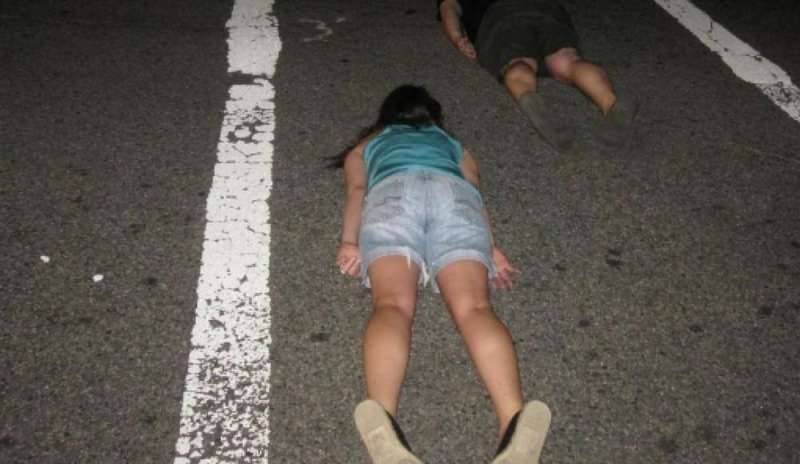 Sdraiati sull'asfalto si fanno selfie mentre passa l'auto